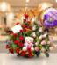 Arreglo de flores con rosas rojas y rosas, flores exóticas naranjas, peluche de oso y globo de feliz cumpleaños sobre mesa en interior