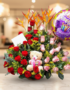 Arreglo de flores con rosas rojas y rosas, flores exóticas naranjas, peluche de oso y globo de feliz cumpleaños sobre mesa en interior