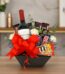 Arreglo floral AMADEA con rosas blancas, eucalipto, lavanda, vino tinto, chocolates variados y lazo rojo en cesta negra.