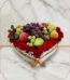 Arreglo floral ARMANI con frutas frescas variadas y rosas rojas dispuestas en una caja blanca en forma de corazón, ideal para
