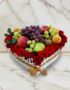 Arreglo floral ARMANI con frutas frescas variadas y rosas rojas dispuestas en una caja blanca en forma de corazón, ideal para