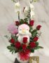 Arreglo floral ALICE con orquídeas blancas, rosas rojas frescas, peluche de pingüino rosa y chocolates Ferrero Rocher, ideal