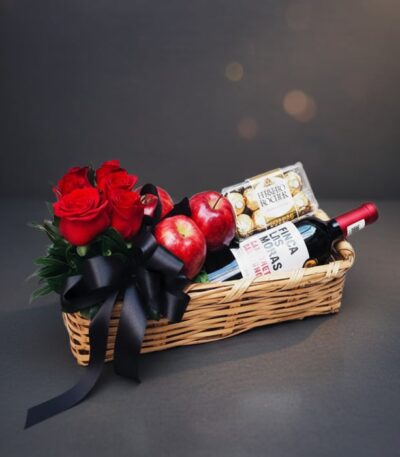 Arreglo ANGELO: Elegante cesta de mimbre con rosas rojas frescas, manzanas rojas, botella de vino tinto Finca Las Moras y caj