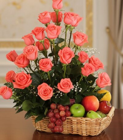 Elegante cesta de regalo con rosas salmón frescas, uvas rojas, manzanas verdes y rojas, peras y limón, ideal para ecommerce.