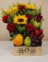 Arreglo floral Adriano con rosas rojas, girasoles vibrantes, naranjas, peras, uvas y fresas en una caja de madera decorada, i