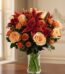 Arreglo Floral ALESSANDRA con rosas naranjas y lirios frescos en un jarrón de cristal, sobre una mesa de madera oscura con un