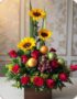 Arreglo floral Batista con rosas rojas, girasoles vibrantes, uvas, mandarinas y manzanas verdes en una base de madera, ideal