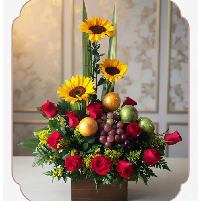 Arreglo Floral Batista: Rosas, Girasoles y Frutas Frescas para Regalar Arreglo floral Batista con rosas rojas, girasoles vibrantes, uvas, mandarinas y manzanas verdes en una base de madera, ideal