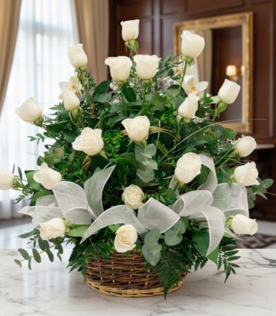 Arreglo floral de rosas blancas y orquídeas en una cesta de mimbre con lazo blanco, sobre una mesa de mármol en un entorno el