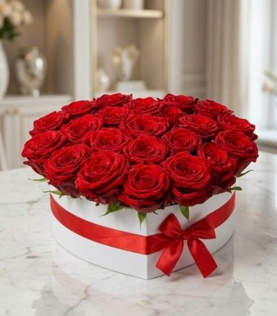 Arreglo floral CAMILA con 24 rosas rojas premium en una elegante caja blanca en forma de corazón, adornada con un lazo rojo,