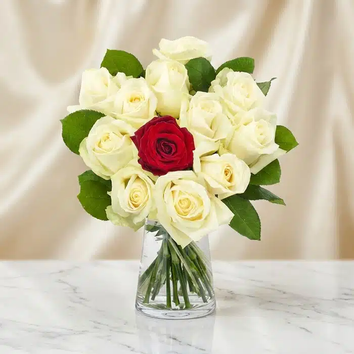 Arreglo Floral CARLA: Diseño Premium con 12 Rosas de Tallo Largo Arreglo floral CARLA con 12 rosas de tallo largo, una roja central y once blancas, en un jarrón de cristal sobre mármol.