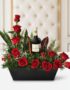 Arreglo floral CINZIA con 12 rosas rojas frescas, follaje verde variado y una botella de vino tinto, presentado en una base n