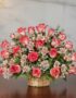 Arreglo floral Emilia con 32 rosas blush frescas, alstroemerias blancas y follaje verde en una canasta de mimbre sobre una me