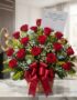 Arreglo floral Escarlata con rosas rojas vibrantes, follaje verde y flores blancas, presentado en una cesta de mimbre con un