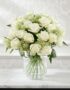 Arreglo floral Estefanía con 24 rosas blancas frescas en un jarrón de cristal sobre una mesa de mármol, con un fondo elegante