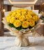 Arreglo floral Evelina con 24 rosas amarillas vibrantes, empaque coreano dorado y lazo, sobre mesa de mármol en un lobby de h