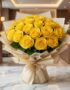 Arreglo floral Evelina con 24 rosas amarillas vibrantes, empaque coreano dorado y lazo, sobre mesa de mármol en un lobby de h