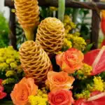 Primer plano extremo del Arreglo Floral Exótico Apolo, mostrando la textura hiperrealista de rosas naranjas, jengibre de colm