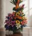 Arreglo floral exótico Armonía con lirios morados, girasoles, aves del paraíso y flores naranjas, sobre una mesa de madera pu