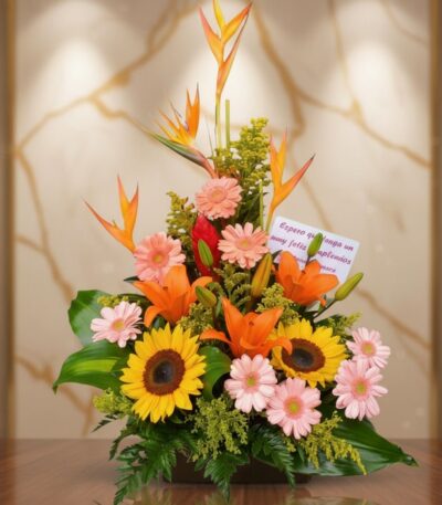 Arreglo floral exótico Columba con aves del paraíso, girasoles, lirios naranjas y margaritas rosadas sobre una mesa de madera