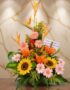 Arreglo floral exótico Columba con aves del paraíso, girasoles, lirios naranjas y margaritas rosadas sobre una mesa de madera