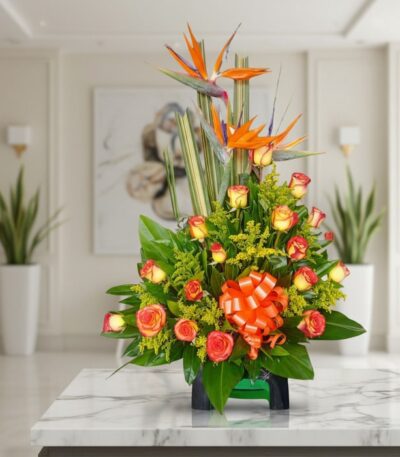 Arreglo floral exótico Esplendor con aves del paraíso y rosas, sobre mesa de mármmol en un elegante lobby de hotel boutique.