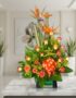 Arreglo floral exótico Esplendor con aves del paraíso y rosas, sobre mesa de mármmol en un elegante lobby de hotel boutique.