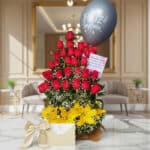 Arreglo floral exótico Gamma con rosas rojas, lirios amarillos y follaje verde, presentado en un entorno elegante y lujoso.