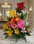 Arreglo floral exótico Paraíso con rosas rojas, amarillas y rosadas, lirios blancos y amarillos, y gerberas naranjas y rojas,