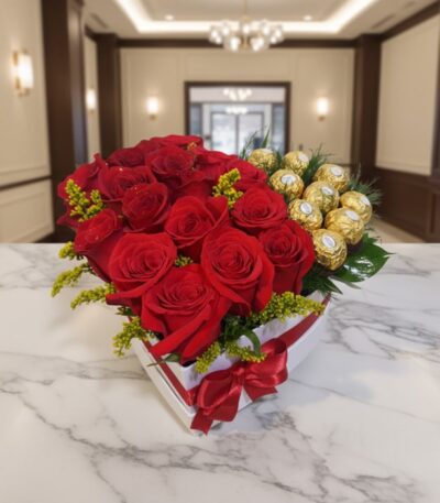 Arreglo floral en forma de corazón con rosas rojas vibrantes y bombones Ferrero Rocher, sobre una mesa de mármol en un elegan