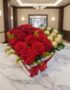 Arreglo floral en forma de corazón con rosas rojas vibrantes y bombones Ferrero Rocher, sobre una mesa de mármol en un elegan