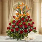 Arreglo floral exótico Tucana con rosas rojas, lirios naranjas y aves del paraíso, sobre mármol, listo para regalo.