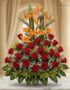 Arreglo floral exótico Tucana con rosas rojas, lirios naranjas y aves del paraíso, sobre mármol en un lobby elegante.