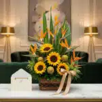 Arreglo floral de lujo con girasoles vibrantes, exóticas aves del paraíso y follaje verde, presentado en una cesta de mimbre