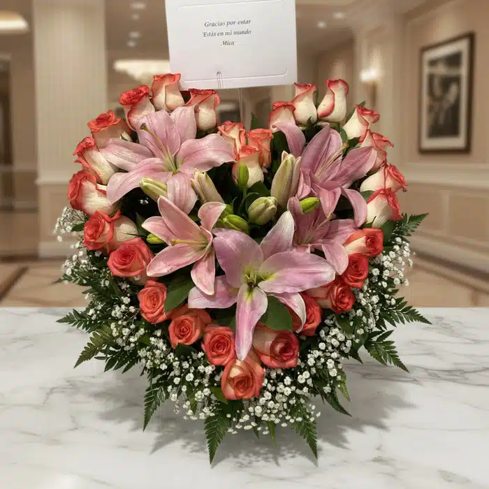Arreglo Floral Feliz Contigo: Lirios y Rosas en Entorno Premium Arreglo floral Feliz Contigo con lirios rosados y rosas bicolor sobre mesa de mármol, fondo elegante de lobby de hotel boutiq