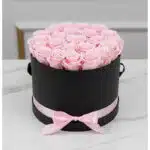 Arreglo floral Francesca con 21 rosas rosadas preservadas en una caja cilíndrica negra con lazo rosa, ideal para regalo.