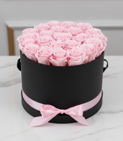Arreglo floral Francesca con 21 rosas rosadas preservadas en una caja cilíndrica negra con lazo rosa, ideal para regalo.