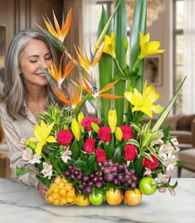 Mujer elegante de cabello gris admirando con deleite un Arreglo Floral con Frutas Akebia, compuesto por aves del paraíso, lir