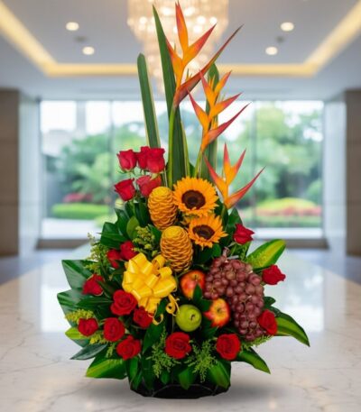 Arreglo floral premium con rosas rojas, girasoles, aves del paraíso, frutas durio, uvas y manzanas, sobre mármol en un lobby