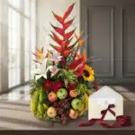 Arreglo floral con frutas exóticas y flores tropicales, incluyendo lirios, girasoles y aves del paraíso, sobre una mesa de ma