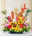 Arreglo floral exótico con heliconias, girasoles, lirios, anturios y frutas tropicales como plátanos, uvas, manzanas y limone