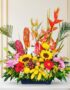Arreglo floral exótico con heliconias, girasoles, lirios, anturios y frutas tropicales como plátanos, uvas, manzanas y limone