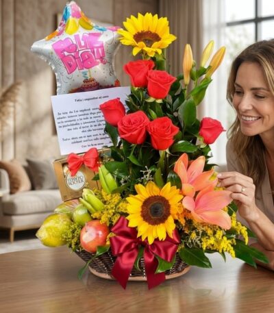 Mujer elegante admirando un arreglo floral con rosas rojas, girasoles, lirios, frutas kiwano y chocolates Ferrero en un hogar