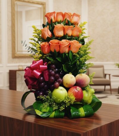 Arreglo floral premium con rosas salmón, uvas, manzanas, duraznos y peras, sobre una mesa de madera pulida en un lobby de hot
