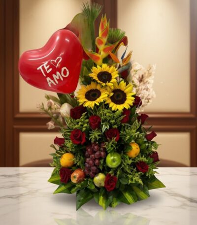 Arreglo floral premium con girasoles, rosas rojas, frutas tropicales (uvas, manzanas, naranjas) y un globo rojo de corazón co