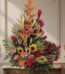 Arreglo floral IDARA con rosas rojas, girasoles, lirios, heliconias y jengibre rojo en un fondo elegante y bien iluminado.
