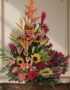 Arreglo floral IDARA con rosas rojas, girasoles, lirios, heliconias y jengibre rojo en un fondo elegante y bien iluminado.