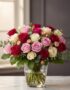 Arreglo floral LUCREZIA con 30 rosas en tonos románticos (rojas, rosas y blancas) en un jarrón de cristal, sobre una mesa de