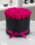 Arreglo Floral Marena con 21 rosas fucsia vibrantes y frescas en una caja redonda negra con lazo fucsia, sobre una mesa de má