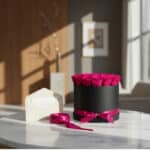 Arreglo floral Marena con 21 rosas fucsia vibrantes en caja negra, tarjeta de regalo y cinta satinada sobre mesa de mármol, l